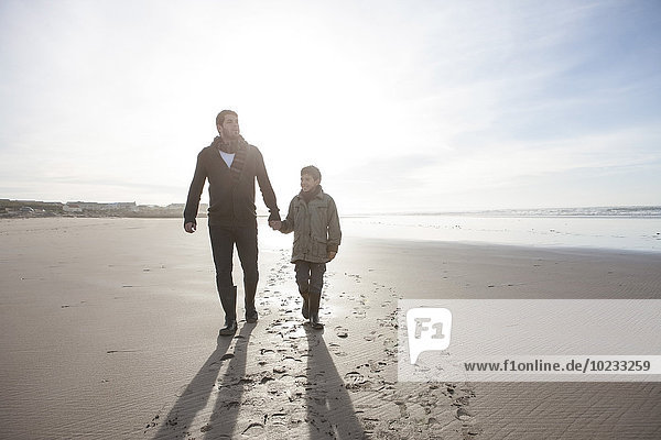 Südafrika  Witsand  Vater und Sohn beim Spaziergang am Strand im Gegenlicht