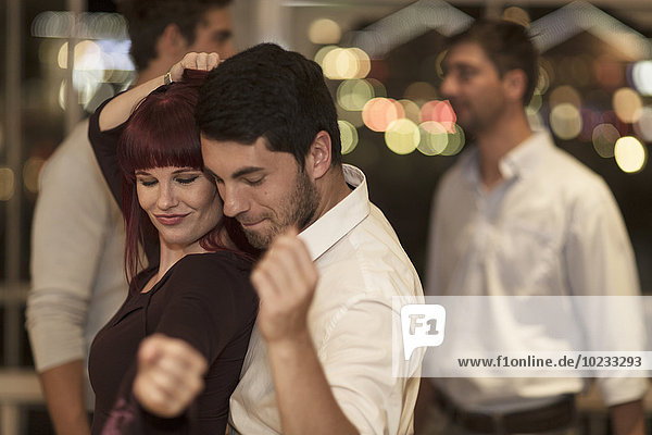 Junge Frau tanzt mit jungem Mann in einer Bar