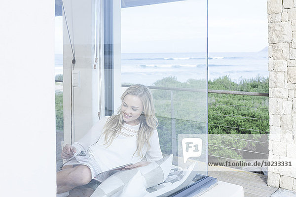 Junge Frau liest Zeitschrift im Strandhaus