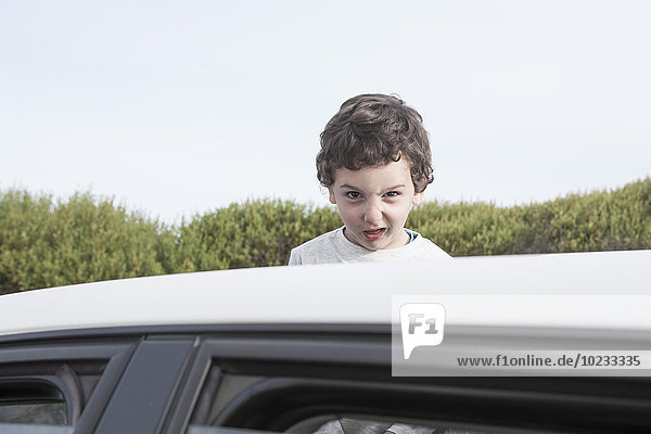 Junge blickt durch ein Schiebedach eines Autos