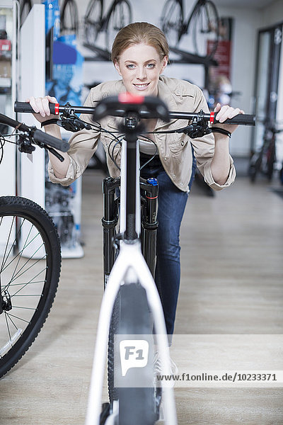 Junge Frau im Fahrradgeschäft auf der Suche nach dem Fahrrad