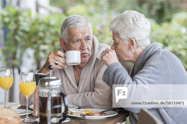 Seniorenpaar beim gemeinsamen Frühstück auf der Terrasse