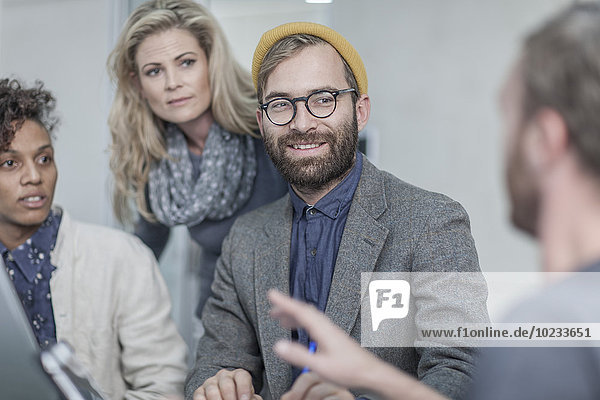 Mann mit Brille und gelber Mütze im Gespräch mit Kollegen