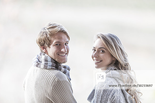 Portrait of smiling young couple looking over their shoulders