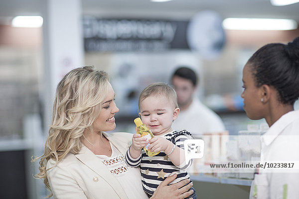 Apothekerin bei der Betreuung des Kunden mit Baby in der Apotheke