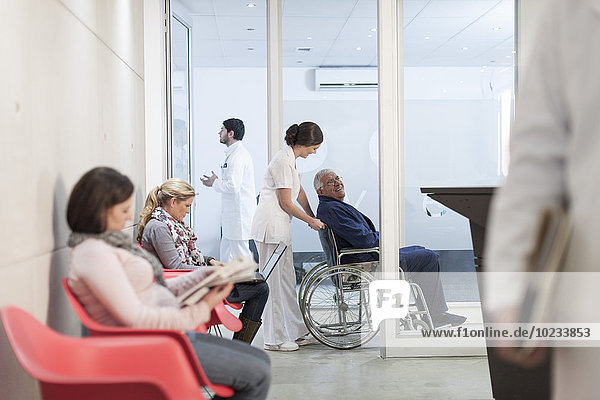Krankenschwester schiebt Patient im Rollstuhl im Wartebereich