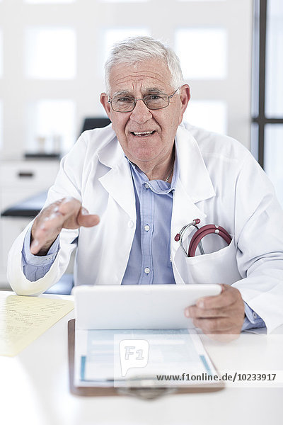 Serious senior doctor at desk discussing patient file