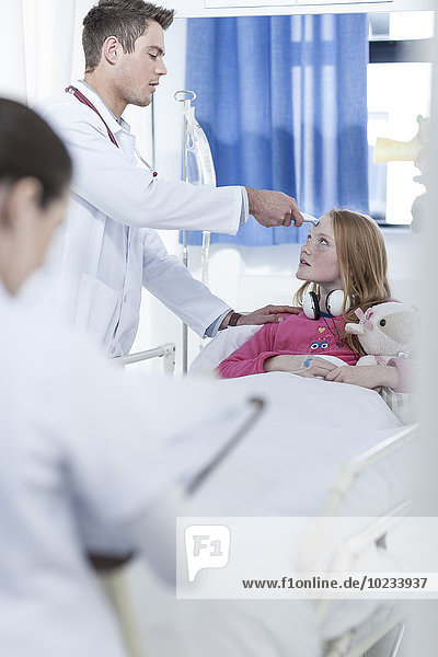 Junge Ärztin untersucht Mädchen im Krankenhausbett