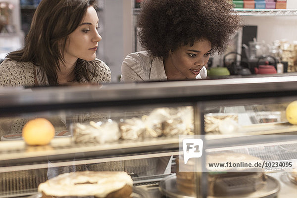 Junge Frauen wählen Kuchen aus der Kuchentheke im Coffee-Shop