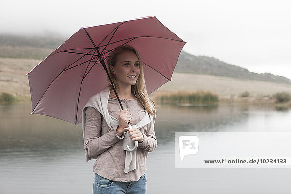 Junge Frau im Regen stehend mit Regenschirm