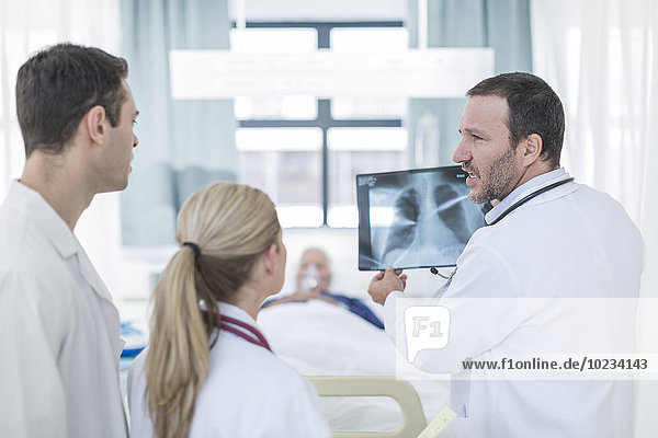 Drei Ärzte mit Röntgenbild im Krankenhauszimmer