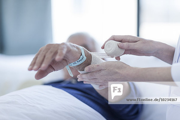 Krankenschwester Bandagierung Arm des älteren Mannes in einem Krankenhaus,  Nahaufnahme