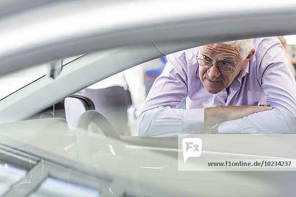 Senior Mann auf der Suche nach einem neuen Auto im Showroom
