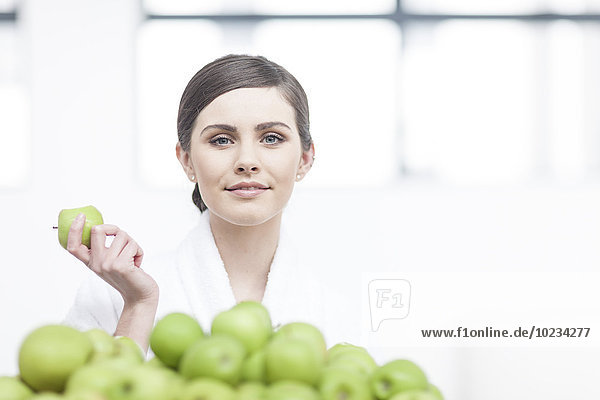Porträt einer lächelnden jungen Frau mit Apfel