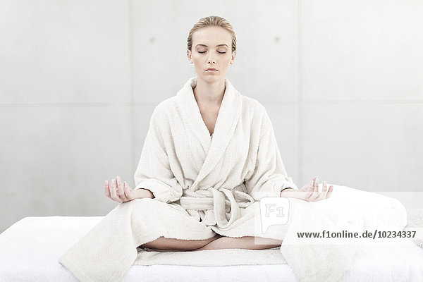 Young woman with bathrobe meditating