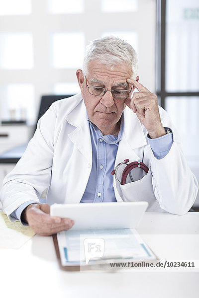 Serious senior doctor at desk looking at patient file