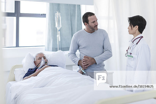 Doctor talking to man visiting patient in hospital