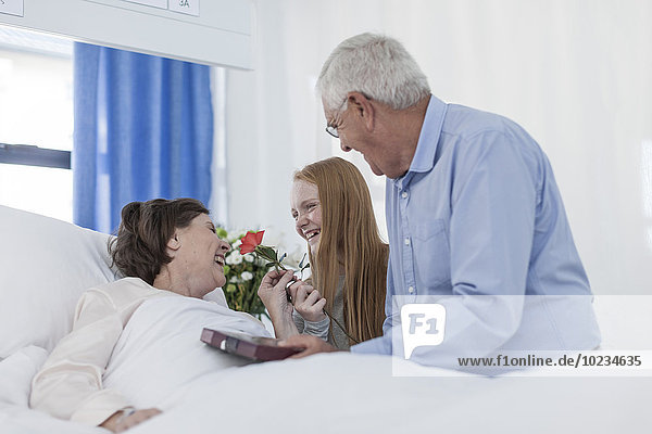 Husband and granddaughter visiting mature patient in hospital