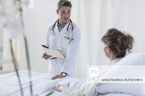 Arzt im Gespräch mit Frau im Krankenhausbett