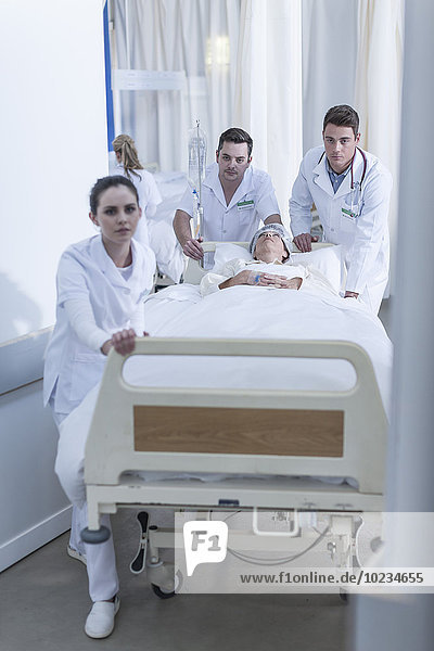 Krankenhauspersonal schiebt Bett mit Patient auf dem Boden