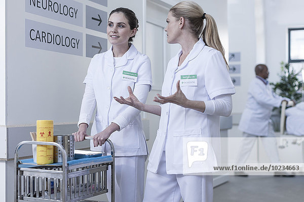 Two nurses in hospital corridor talking