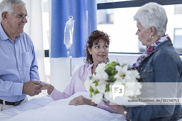 Senior couple visiting mature patient in hospital