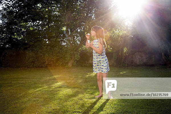 Girl blowing soap bubbles in a garden