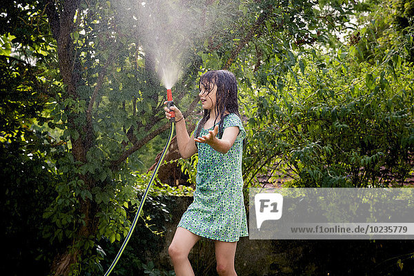 Girl cooling herself with garden hose