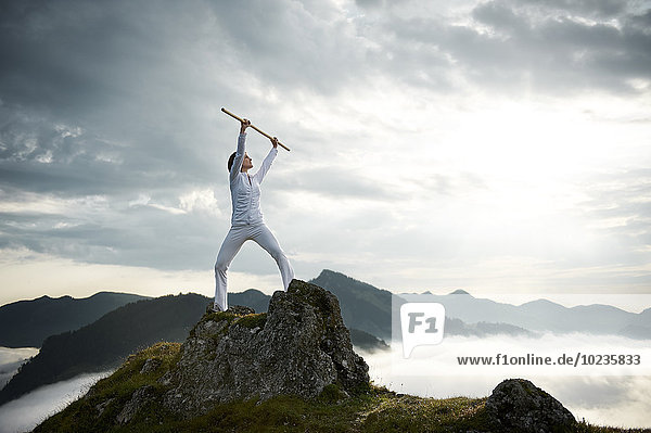 Österreich  Kranzhorn  Mittlere erwachsene Frau beim Stockkampf auf dem Berggipfel