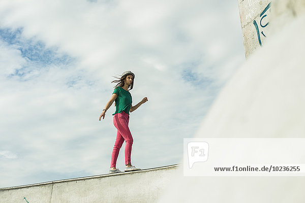 Junge Frau balanciert auf einer Wand in einem Skatepark