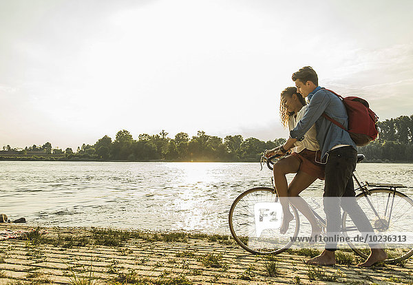 Junges Paar mit Fahrrad am Flussufer