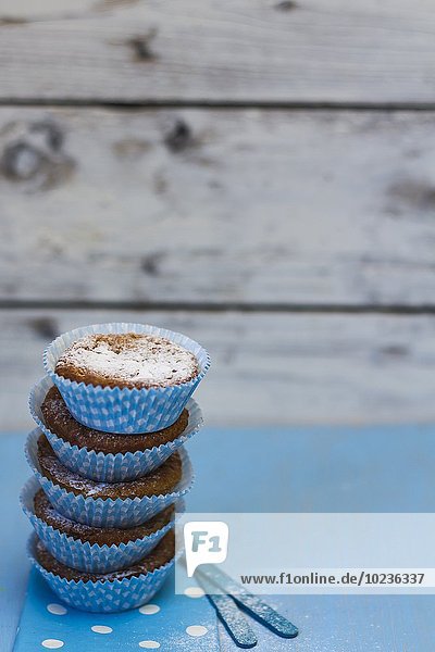 Gestapelte Muffins mit Puderzucker in blauen Papierförmchen