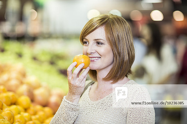 Junge Frau im Supermarkt hält orange