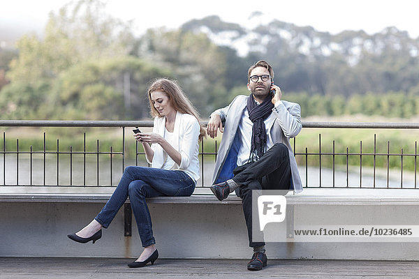 Paar mit Smartphones auf der Terrasse