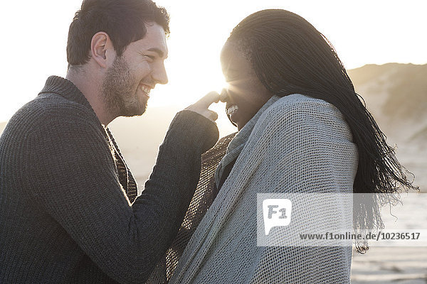 Südafrika  Kapstadt  glückliches junges Paar am Strand bei Sonnenuntergang
