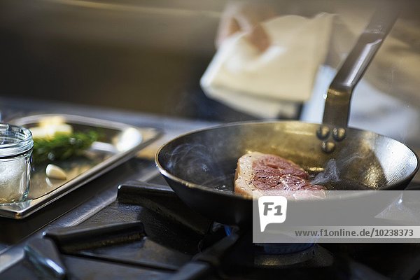 A chef preparing a steak in a commercial kitchen