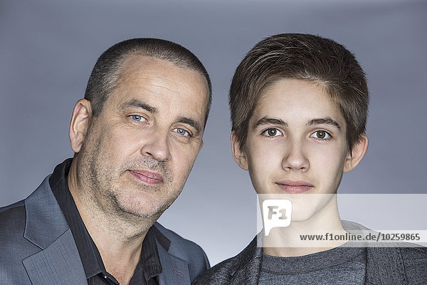 Porträt eines selbstbewussten Vaters mit Sohn über grauem Hintergrund