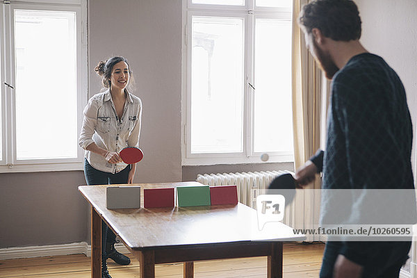 Junge Frau beim Tischtennisspielen mit Mann zu Hause