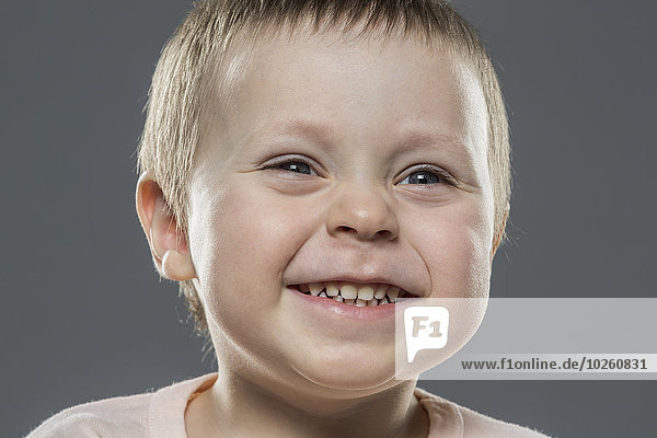 Close-up of happy boy against gray background