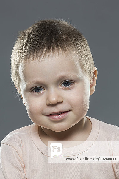 Porträt des süßen Jungen vor grauem Hintergrund