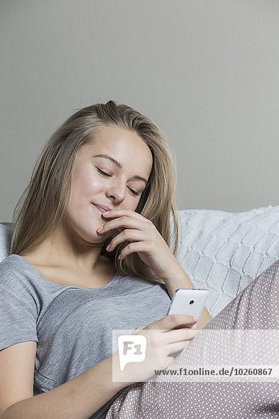 Teenager Mädchen mit Smartphone auf dem Sofa zu Hause