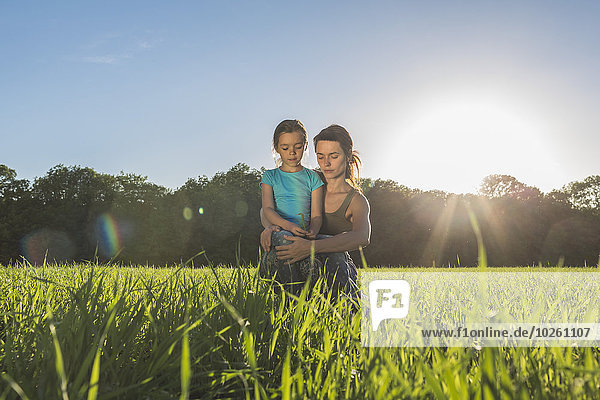 Mother and daughter sitting on grassy field