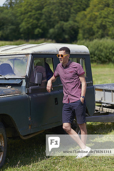 Full length of young man leaning on jeep in park