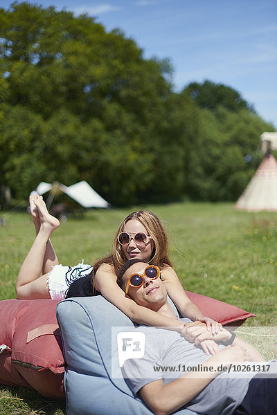 Loving couple lying on pillows while glamping  teepee in background