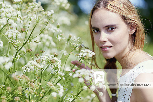 Portrait of beautiful woman by flower plants in park