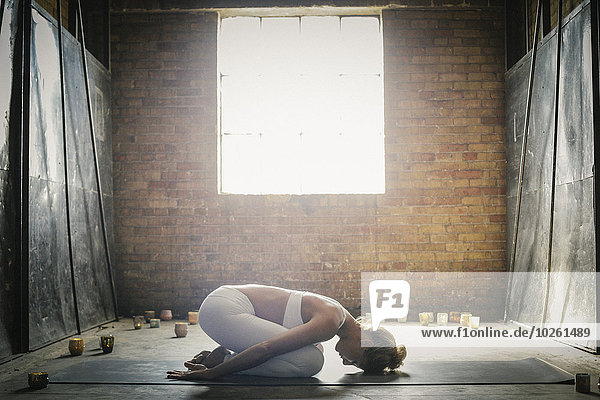 beleuchtet Frau Boden Fußboden Fußböden kniend strecken Kerze umgeben Yoga blond Matte Pose