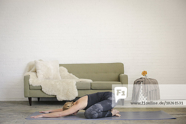 Frau kniend schwarz frontal Yoga Turnanzug blond Leggins Matte