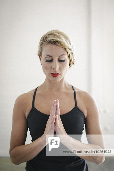 stehend Zusammenhalt Frau geschlossen schwarz Yoga Turnanzug blond