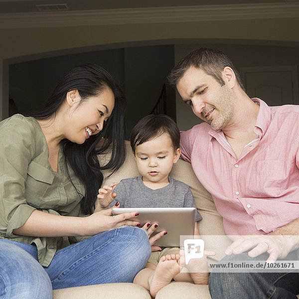 sitzend sehen Couch lächeln Sohn jung Tablet PC Seitenansicht Mann und Frau