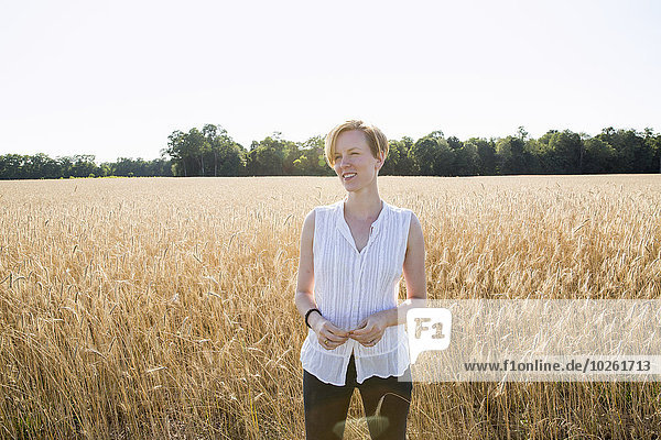Half length portrait of a young woman standing in a cornfield.